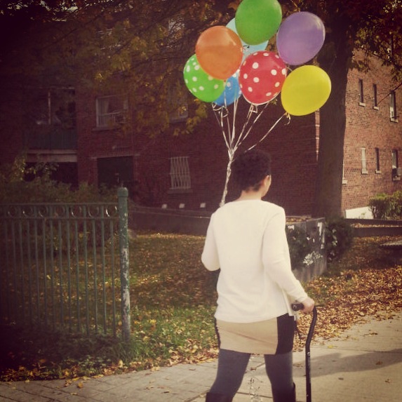 Cane in one hand, balloons in the other.